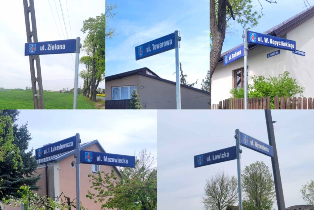Niebieskie tabliczki z herbem gminy oraz białym napisem z nazwami.