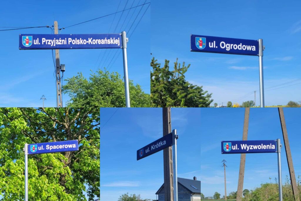Niebieskie tabliczki z herbem gminy oraz białym napisem z nazwami.